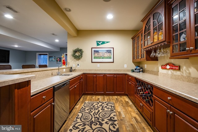 kitchen with kitchen peninsula, light hardwood / wood-style flooring, stainless steel dishwasher, and sink