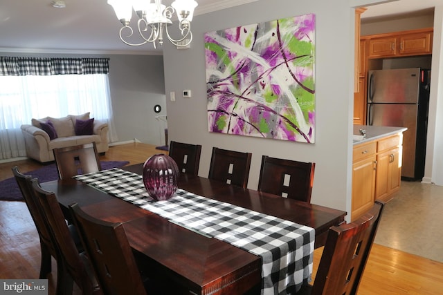 dining room featuring light hardwood / wood-style flooring, crown molding, and an inviting chandelier