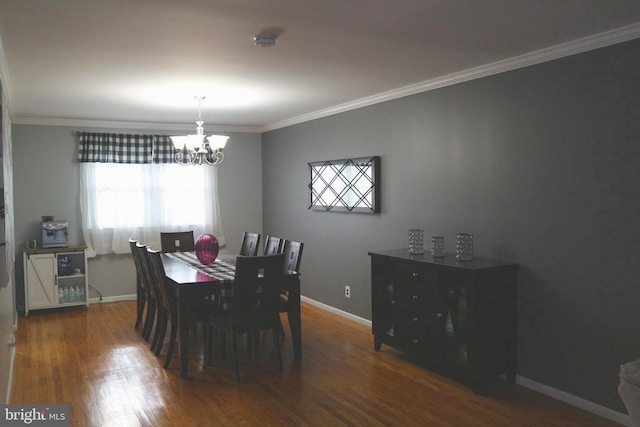 dining space featuring dark hardwood / wood-style flooring, ornamental molding, and a notable chandelier