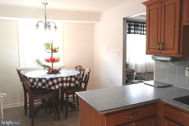 kitchen featuring a notable chandelier, decorative backsplash, kitchen peninsula, and hanging light fixtures