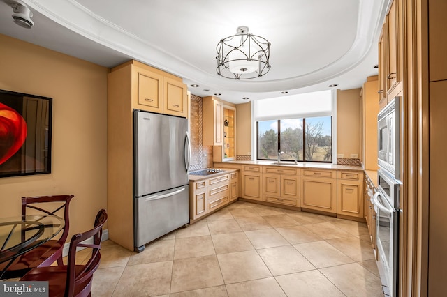 kitchen featuring sink, light tile patterned floors, a tray ceiling, stainless steel appliances, and light brown cabinets