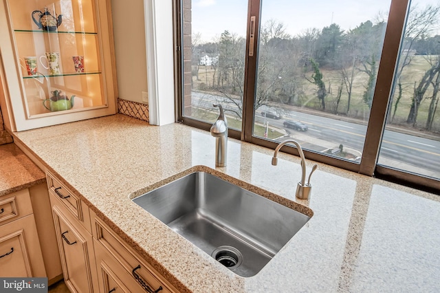 kitchen featuring light stone counters and sink