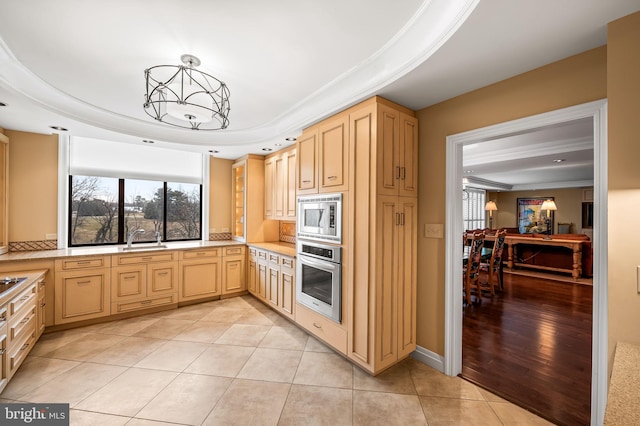 kitchen with stainless steel appliances, a raised ceiling, sink, and light brown cabinetry