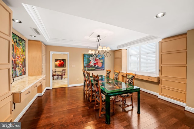 dining space featuring an inviting chandelier, ornamental molding, a tray ceiling, and dark wood-type flooring