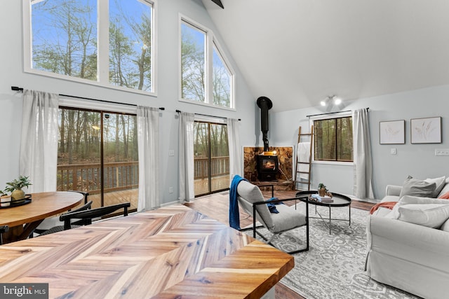 living room featuring a wood stove, a towering ceiling, and light parquet flooring