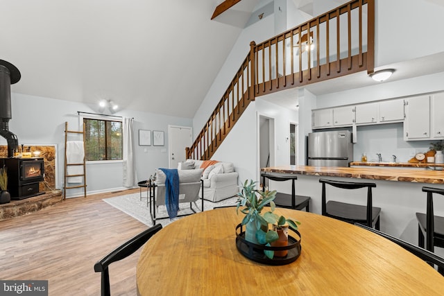 dining room featuring light wood-type flooring, a wood stove, and lofted ceiling