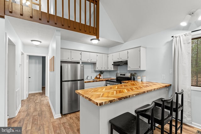 kitchen featuring lofted ceiling, sink, light hardwood / wood-style flooring, white cabinetry, and stainless steel appliances