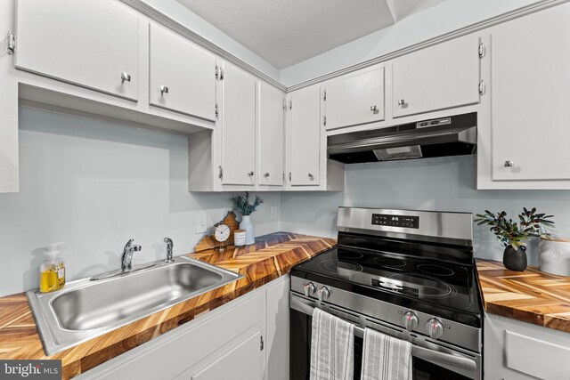 kitchen with wood counters, gas stove, white cabinetry, and sink