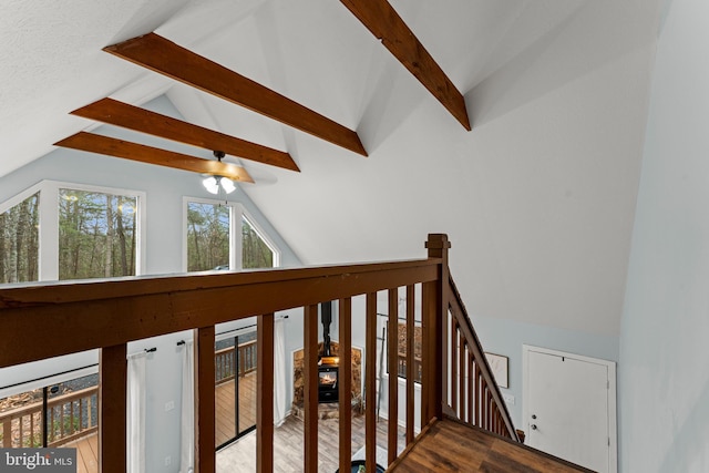 staircase with vaulted ceiling with beams, hardwood / wood-style flooring, and ceiling fan