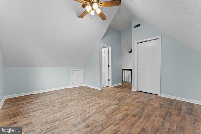 additional living space with a textured ceiling, light hardwood / wood-style flooring, ceiling fan, and vaulted ceiling