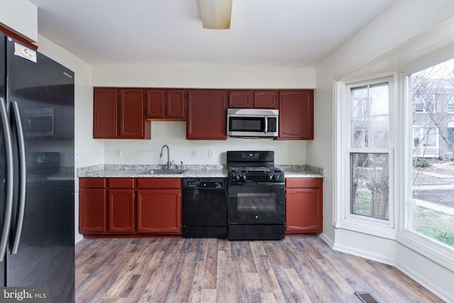 kitchen featuring sink, black appliances, and hardwood / wood-style flooring