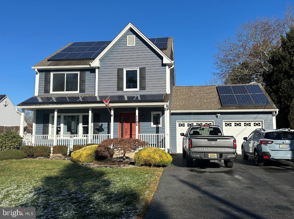 view of property with covered porch, solar panels, and a garage