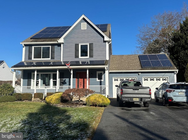 view of property with covered porch, solar panels, and a garage