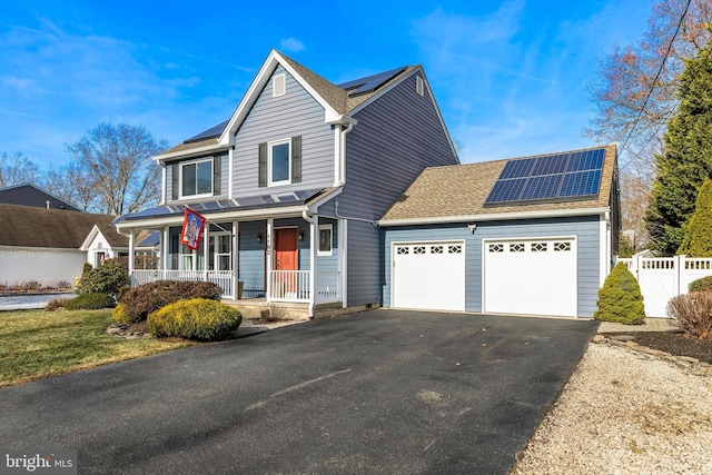 front of property featuring solar panels, a porch, and a garage