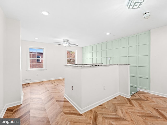 interior space featuring green cabinets, ceiling fan, light parquet flooring, and light stone counters