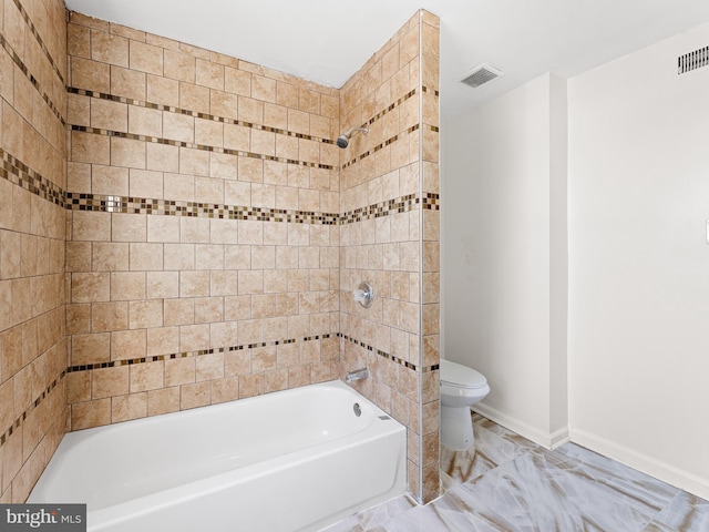 bathroom with tiled shower / bath combo and toilet