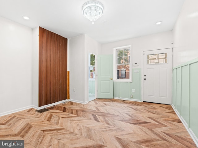 foyer featuring light parquet flooring and a notable chandelier