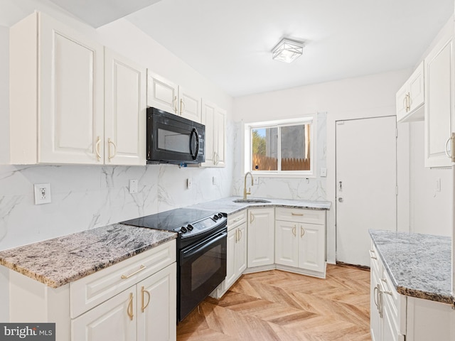 kitchen featuring light stone countertops, white cabinetry, sink, light parquet flooring, and black appliances