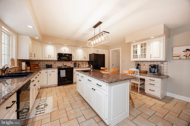 kitchen featuring sink, white cabinets, black appliances, and a kitchen island with sink