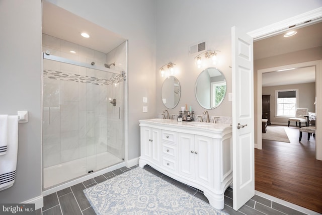 bathroom featuring a shower with shower door and vanity