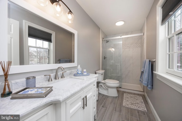 bathroom featuring a shower with shower door, vanity, and toilet