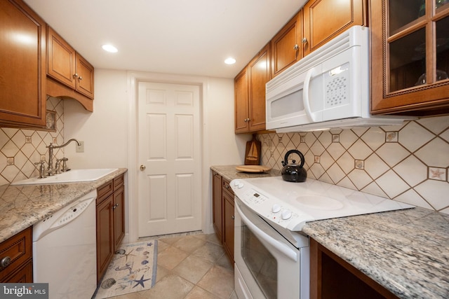 kitchen featuring tasteful backsplash, sink, white appliances, light tile patterned floors, and light stone counters