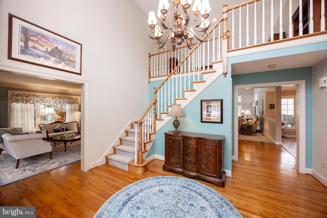 staircase featuring a towering ceiling, a chandelier, and hardwood / wood-style floors