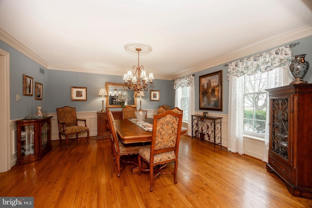 dining space with a chandelier, crown molding, and wood-type flooring