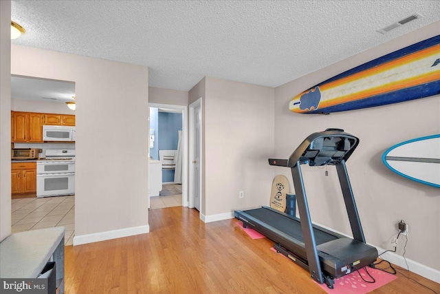 workout area with a textured ceiling and light hardwood / wood-style floors