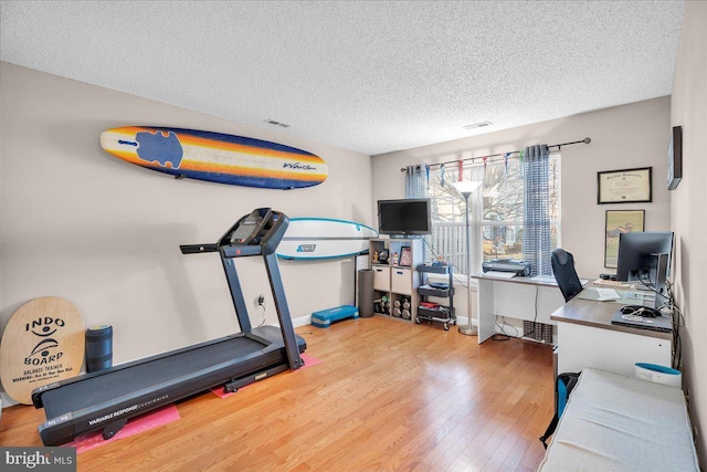 exercise area with hardwood / wood-style floors and a textured ceiling