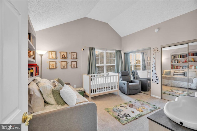 carpeted bedroom featuring a crib, a textured ceiling, and vaulted ceiling