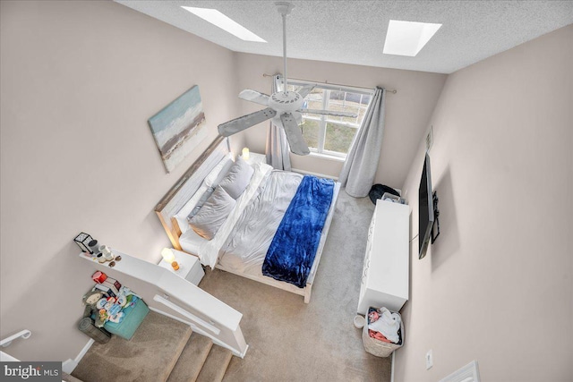 carpeted bedroom with ceiling fan, a textured ceiling, and a skylight