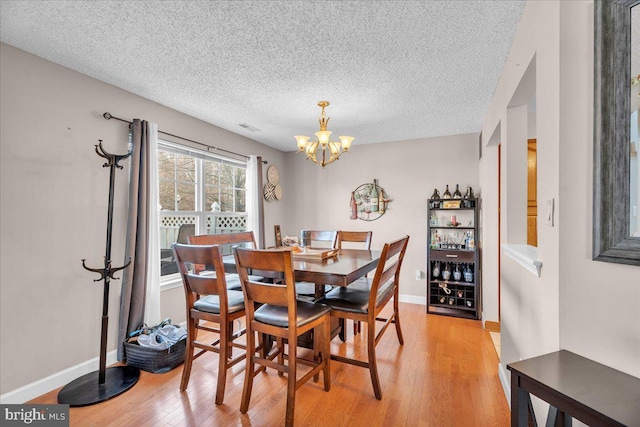 dining space featuring a chandelier, a textured ceiling, and light hardwood / wood-style flooring