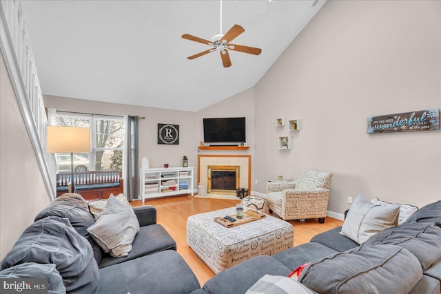 living room featuring ceiling fan, light hardwood / wood-style floors, a fireplace, and vaulted ceiling