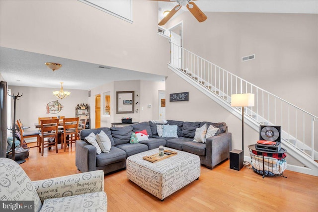 living room featuring ceiling fan with notable chandelier, wood-type flooring, and high vaulted ceiling