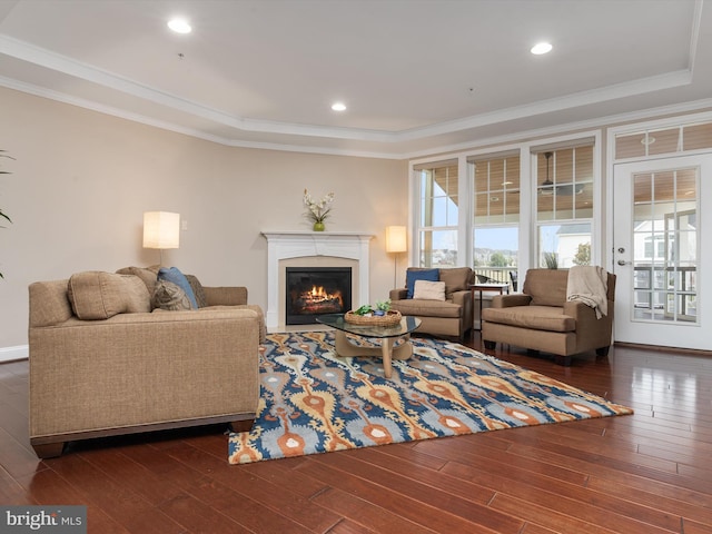 living room with dark wood finished floors, a glass covered fireplace, recessed lighting, and crown molding