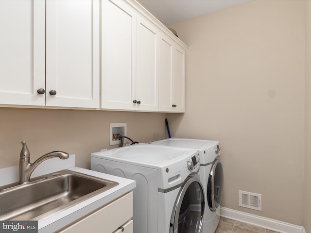 laundry room with washing machine and clothes dryer, visible vents, baseboards, cabinet space, and a sink