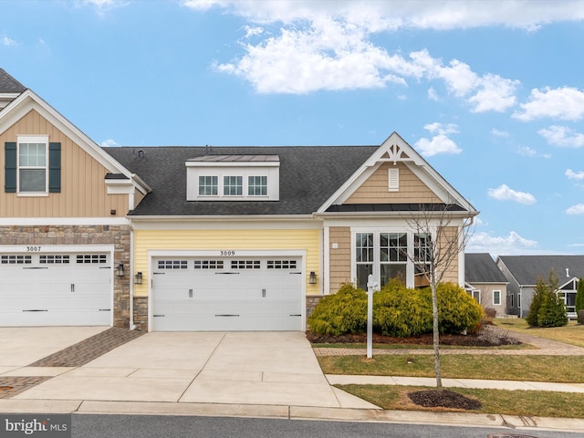 view of front of home featuring stone siding, driveway, and a shingled roof