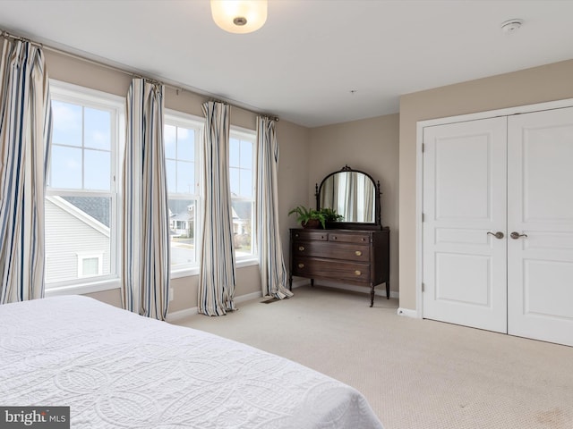 bedroom featuring light colored carpet, baseboards, and a closet