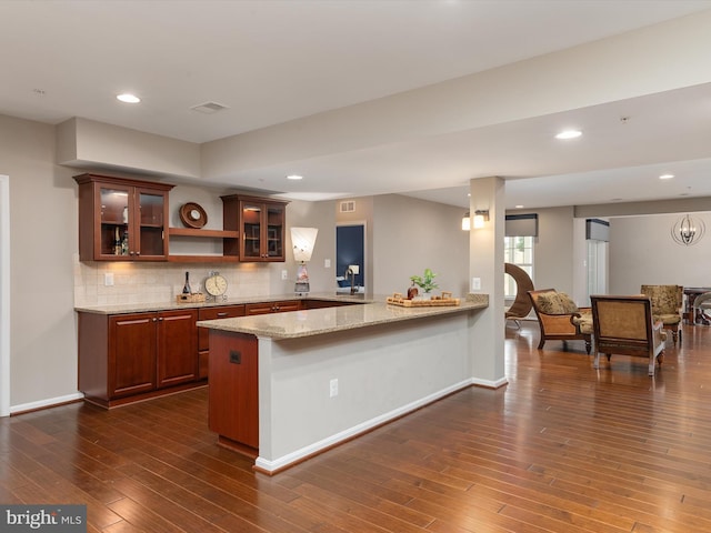 kitchen featuring glass insert cabinets, dark wood finished floors, recessed lighting, a peninsula, and decorative backsplash