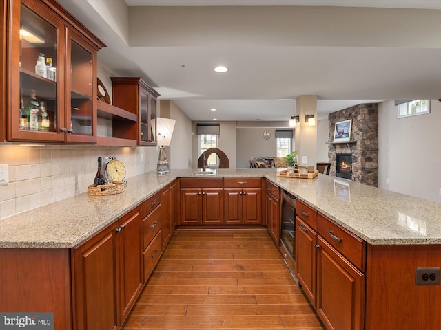 kitchen with wood finished floors, beverage cooler, light stone countertops, a peninsula, and tasteful backsplash