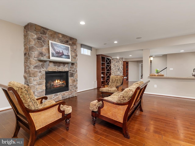 living area with hardwood / wood-style floors, stairway, baseboards, recessed lighting, and a stone fireplace