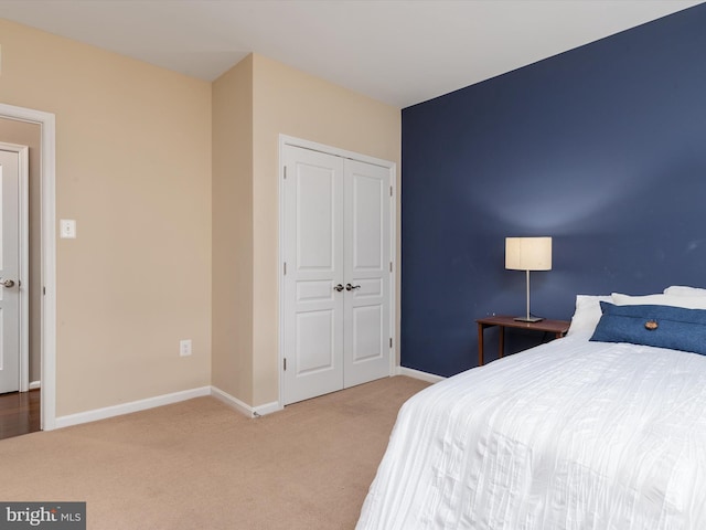 carpeted bedroom with a closet and baseboards