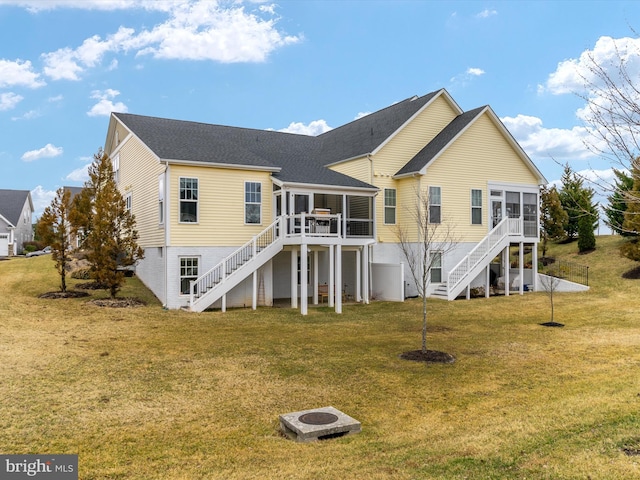 back of house with stairway, a lawn, a fire pit, and a sunroom