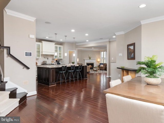 living room with dark wood finished floors, crown molding, and stairway