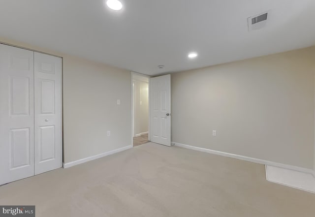 unfurnished bedroom featuring light colored carpet and a closet