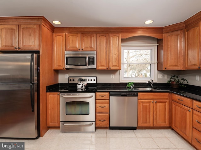 kitchen featuring appliances with stainless steel finishes, sink, and dark stone countertops