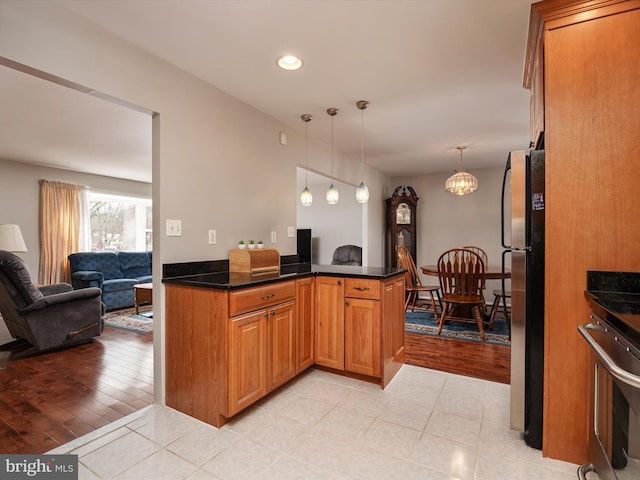 kitchen featuring a chandelier, light tile patterned floors, kitchen peninsula, pendant lighting, and stainless steel appliances