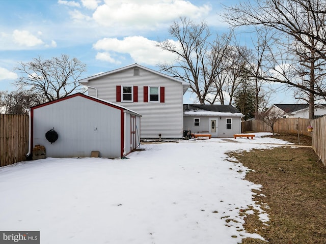 snow covered back of property with an outbuilding