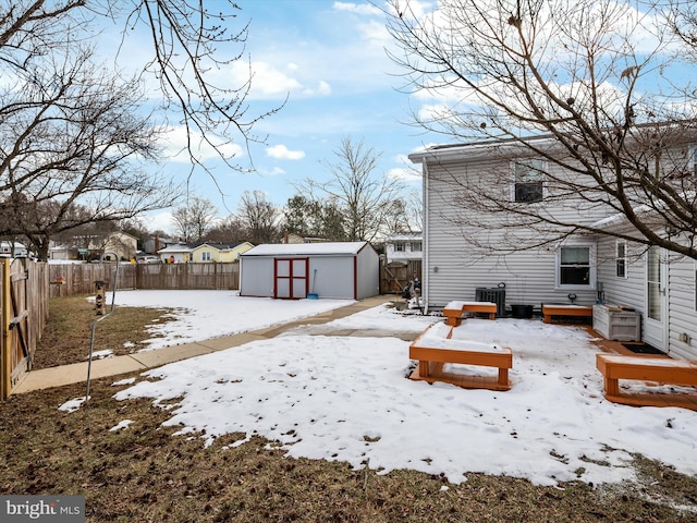 yard layered in snow with a storage unit and central AC unit